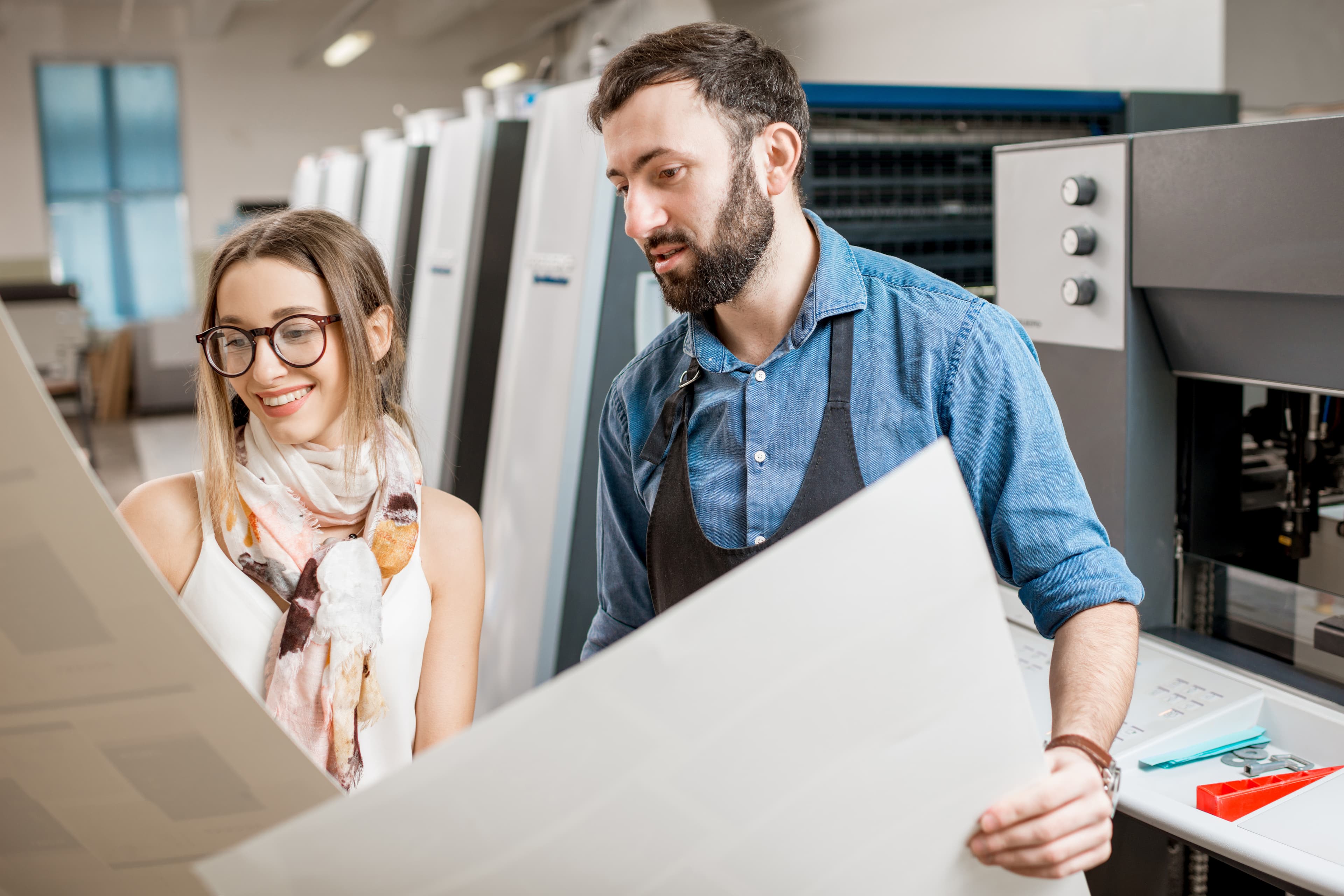 Two people looking at print production proof sheets